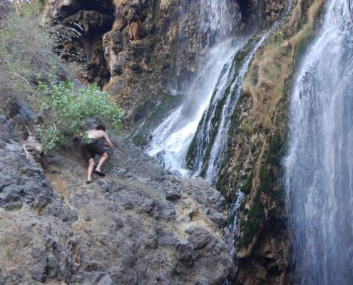 Escalar escarpadas rocas con zapatillas como este aventurero huésped de Safari no es necesario para llegar a las cascadas de Ngare Sero, en la zona del lago Natron.
